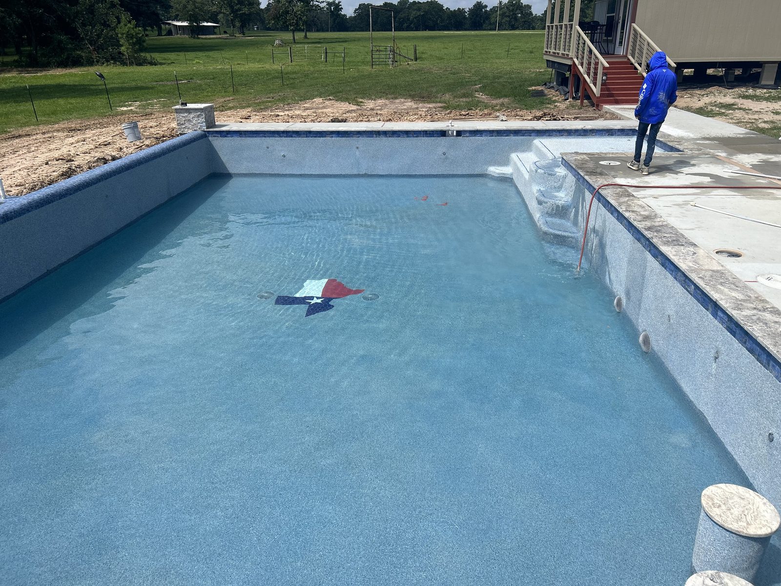 Freshly filled pool with a Texas flag mosaic set into the floor on a country property